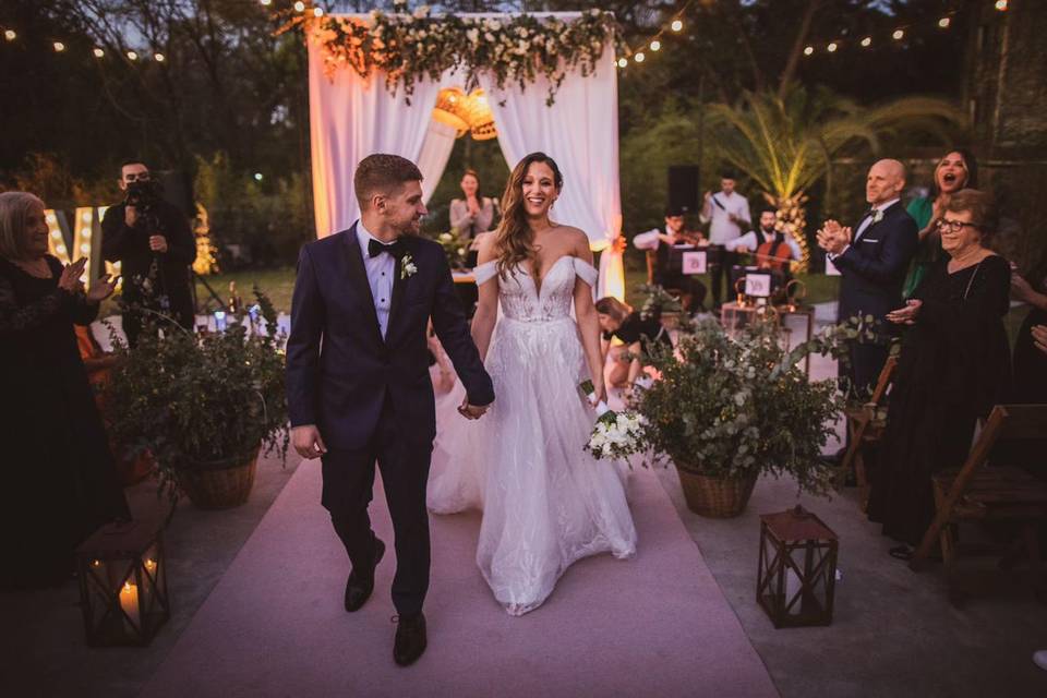 Novios caminando por un pasillo en medio de los invitados